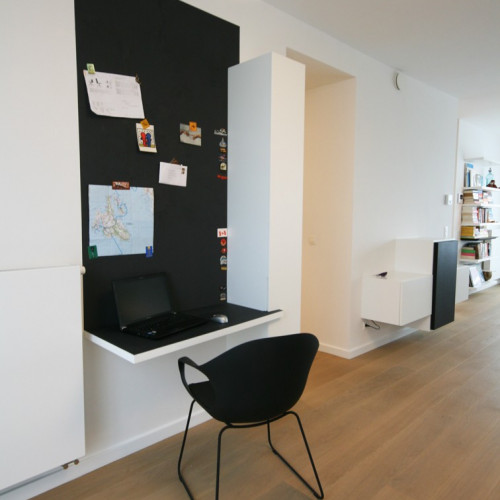 Net als bij de andere interieurelementen zorgden we voor een strakke afwerking. De details maken het verschil, hier werd de draaideur voorzien van ingefreesde handgreep. Dit bureau bewijst alvast dat je niet veel ruimte nodig hebt om een thuiskantoor te creëren.  Een zwevende legger met blinde bevestiging dient als bureaublad. Naast en boven de hangkast creërden we een magneetmuur, dewelke qua hoogte gelijk komt met de andere zwarte elementen in het interieur. Kast-ID Antwerpen